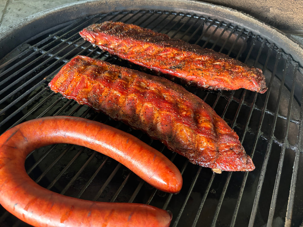 Grilled Berkshire baby back ribs and sausage on a charcoal grill.