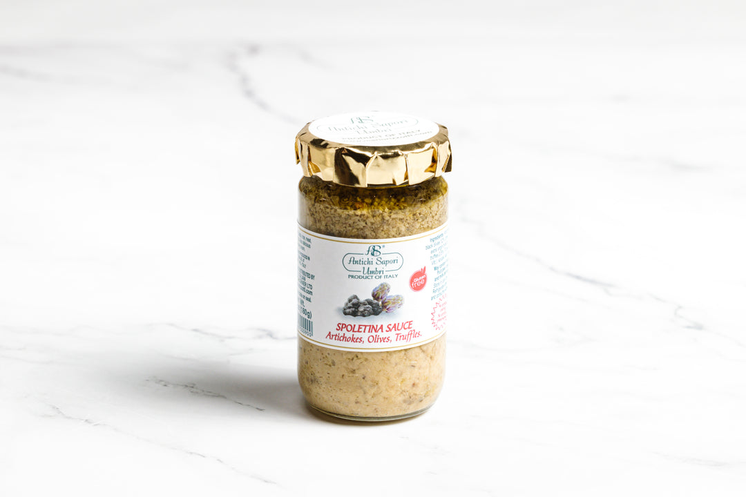 Jar of Spoletina sauce with gold foil top on a marble surface.