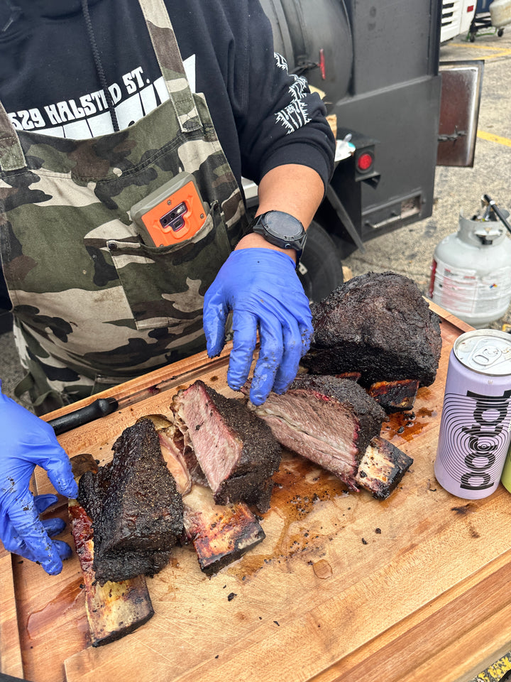 Close-up of sliced Wagyu short ribs, showing juicy meat and charred edges, held by gloved hands.