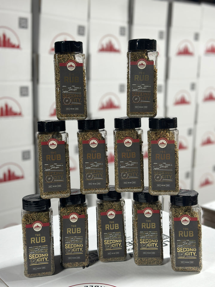 Stacked bottles of The Rub seasoning, showcasing its flavorful blend for grilling and cooking.