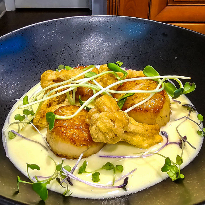 U-10 scallops topped with microgreens in a creamy sauce.