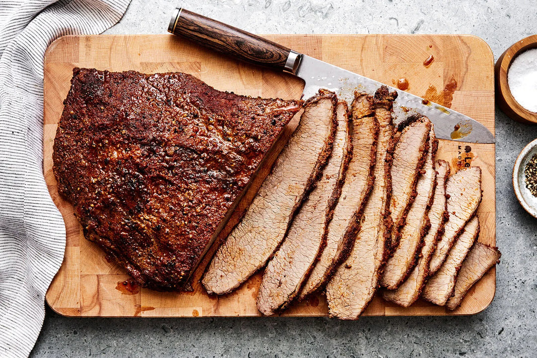 Juicy Prime Angus Beef Smoked Brisket, sliced on a wooden board with a carving knife. Ready to eat!