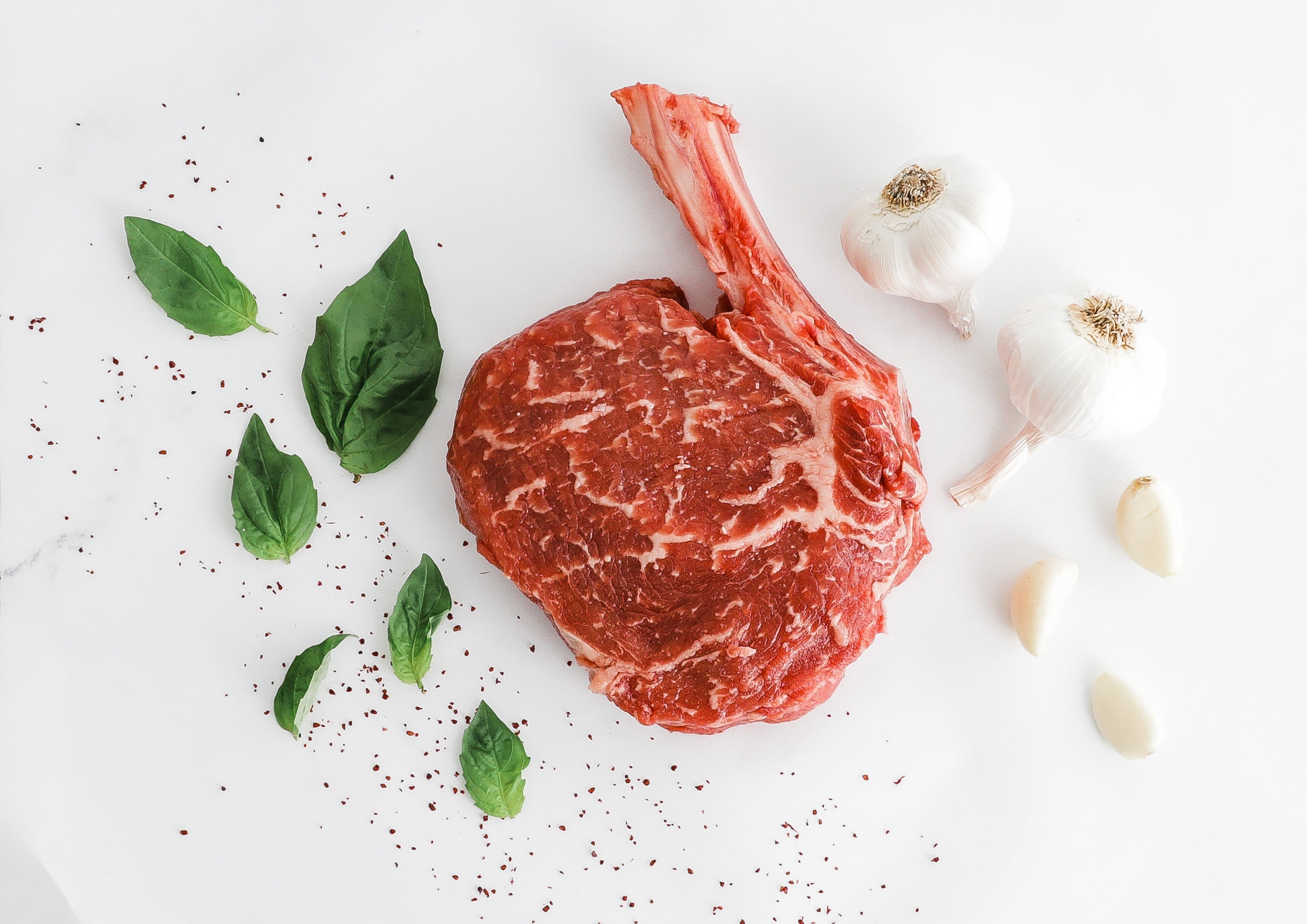 Cut of Prime Bone-in Ribeye from Second City Prime with herbs and garlic.
