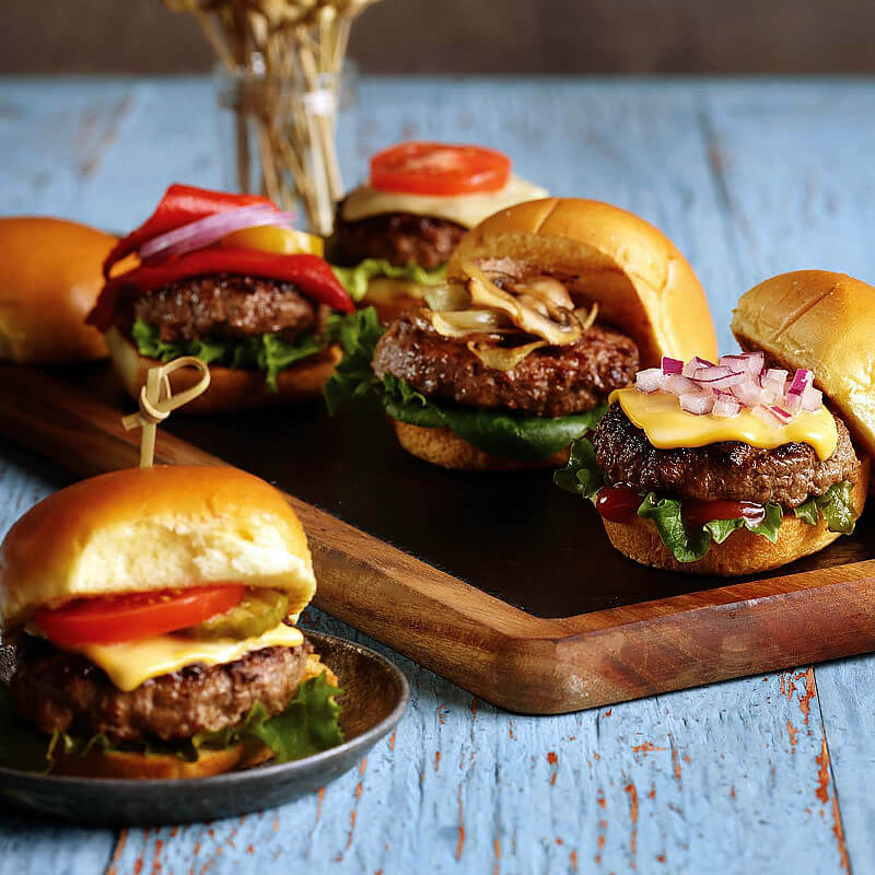 Juicy USDA Prime Brisket, Short Rib & Chuck Sliders (8 pack) on a wooden board with various toppings. Ready to grill!