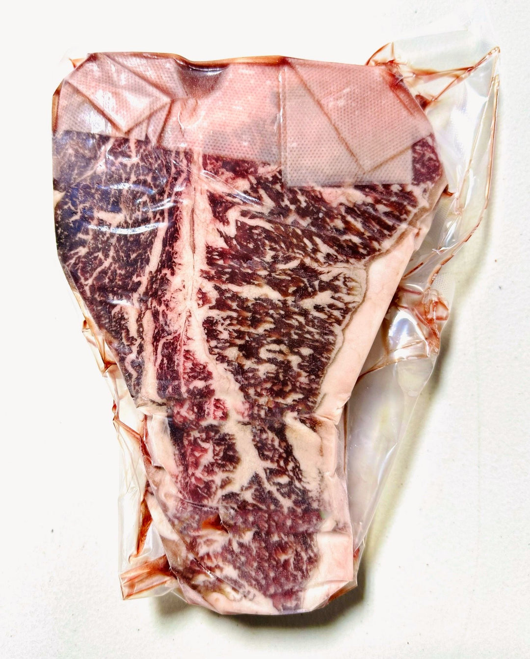 Vacuum-sealed 32oz Australian Wagyu T-Bone Steak with rich marbling, showcasing MS 6-7 quality.