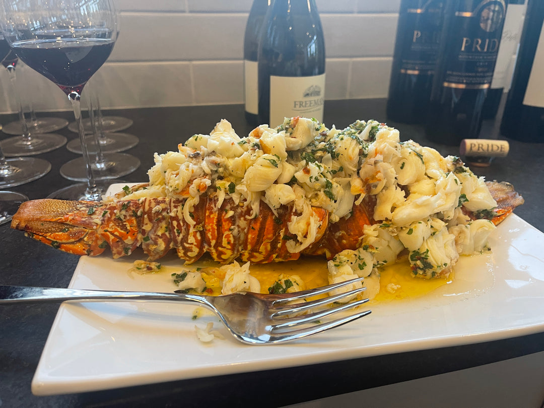 Grilled lobster tail topped with crab meat and herbs, served with wine.