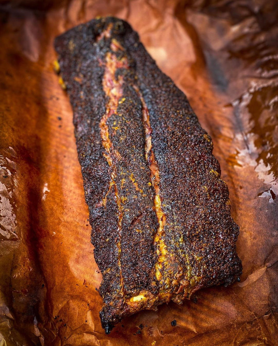 Smoked Berkshire baby back rib on butcher paper with a charred crust.