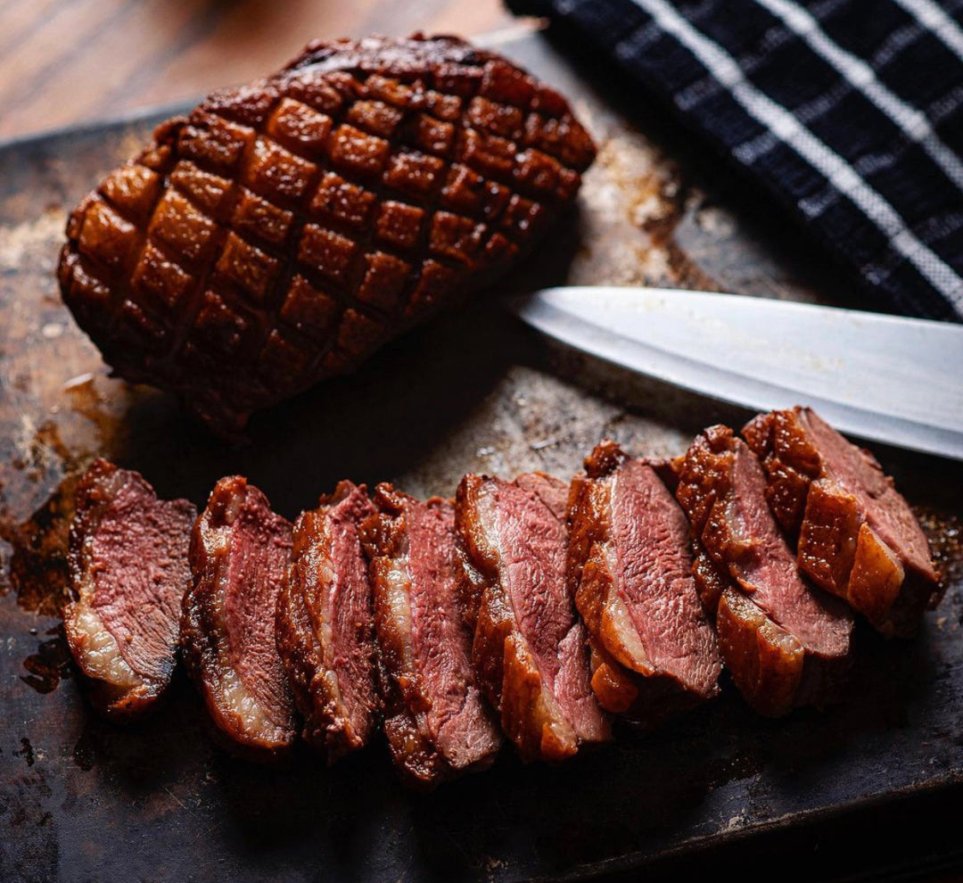 Sliced Moulard duck breast showcasing rich color and texture on a cutting board.