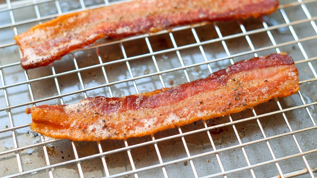 Two slices of Second City Prime's hickory-smoked Berkshire thick-cut bacon on a wire rack.