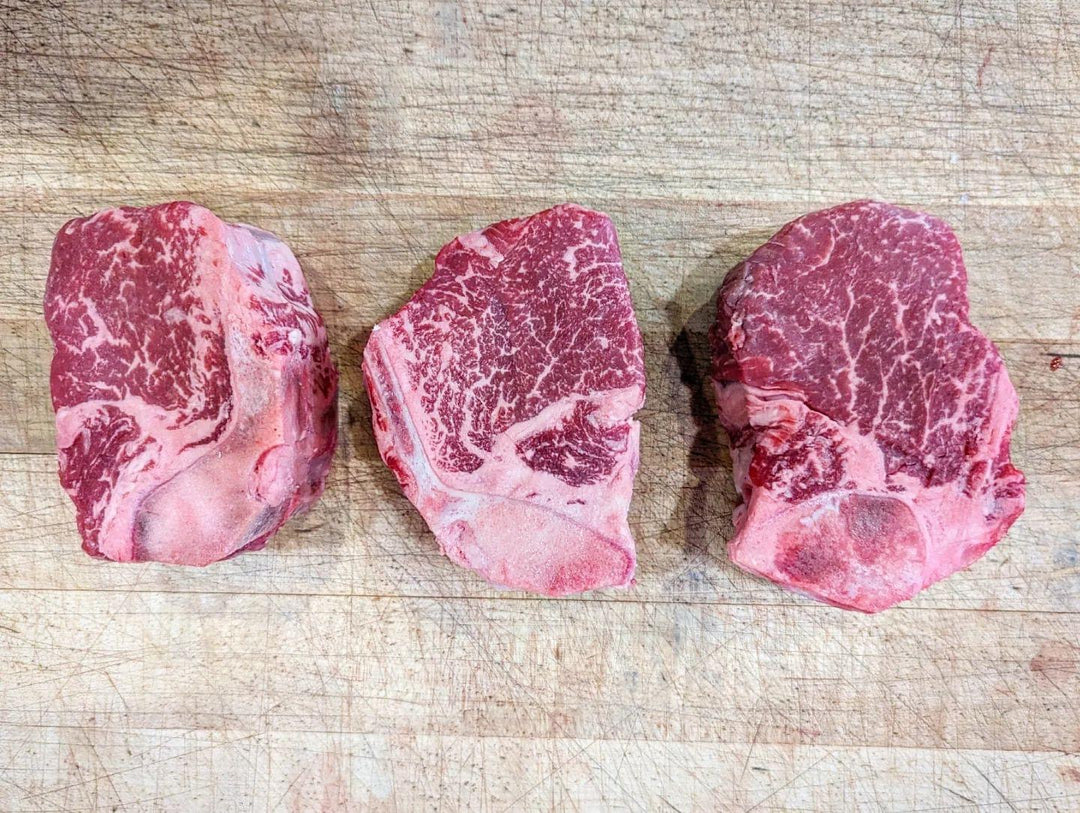 Three raw USDA Prime Meyer Ranch Bone-In Filet Mignon steaks on a wooden board.