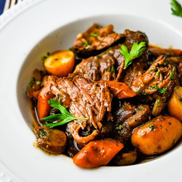 Tender Australian Wagyu Chuck Roast with carrots and potatoes, garnished with parsley.